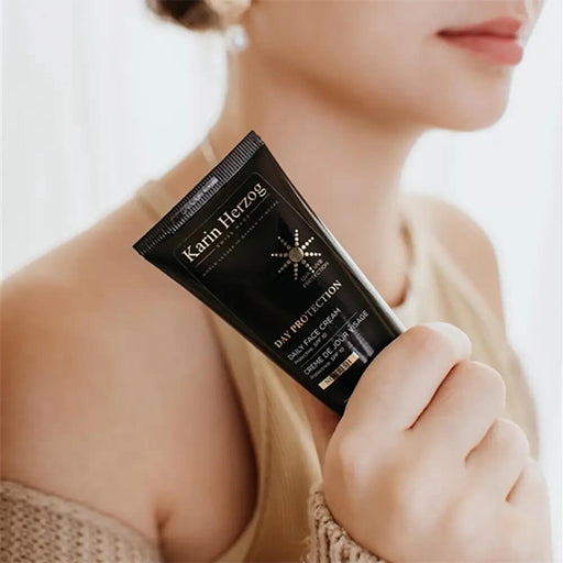 A woman holding a tube of Karin Herzog daily face cream, designed for day protection and effective anti-ageing skincare.