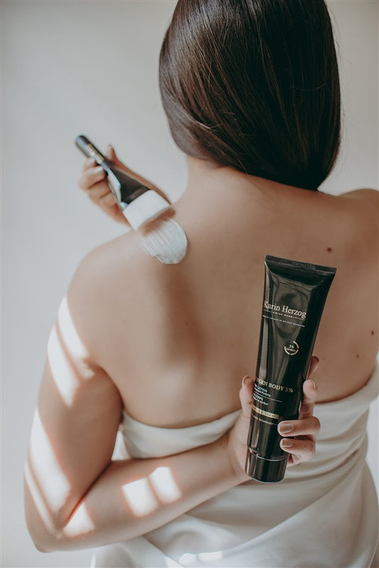 A woman applying Karin Herzog Oxygen Body 3% treatment on her back, a powerful antiseptic and antimicrobial body treatment with hydrating and firming properties.