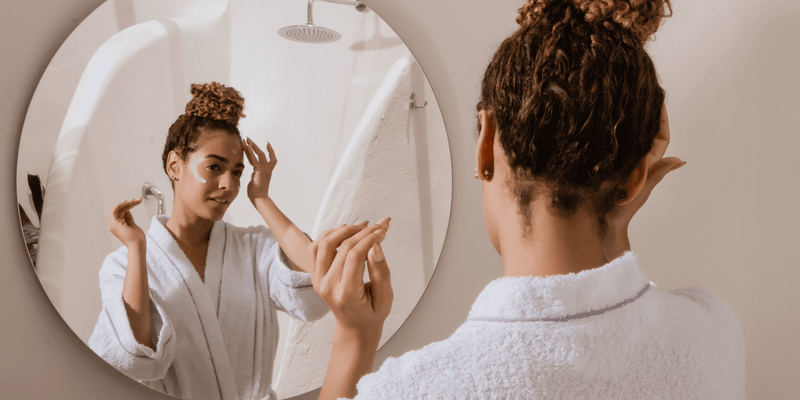 Woman applying skincare in the mirror while wearing a bathrobe, reflecting the expert-backed, oxygen-powered skincare of Karin Herzog – where Swiss science meets radiant results.