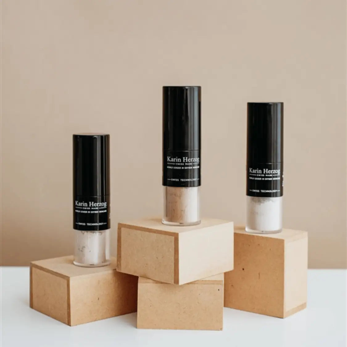 Karin Herzog Face Powder bottles displayed on wooden blocks, designed to set make up and leave skin smooth, fresh, and luminous.