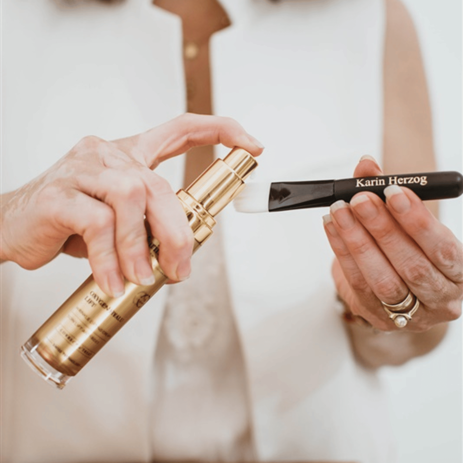 Applying Karin Herzog Oxygen Hyalu Lift 30ml — a luxurious anti-aging serum with hyaluronic acid and active oxygen, shown in a sleek gold pump bottle during skincare routine.